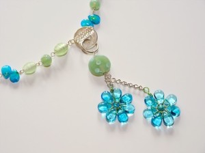 Beautiful flowers dangle as pendants from beaded 24" chain, closed with front clasp. Aquas and greens.