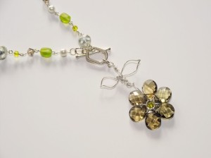 Flower pendant hangs from 18" chain highlighted by pearls, crystal and fancy glass beads.