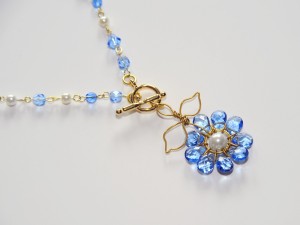 Blue glass flower petals surround pearl center and hang from 17" beaded golden chain. Closed with front clasp.